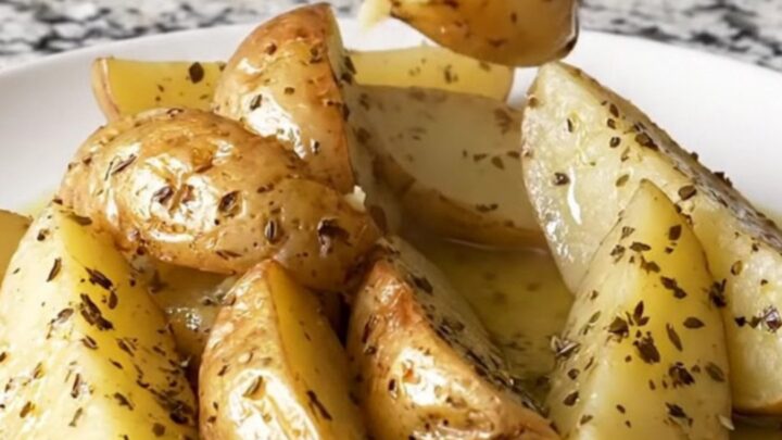 A close-up of tender golden potato wedges in a slow cooker, seasoned with herbs and lemon.