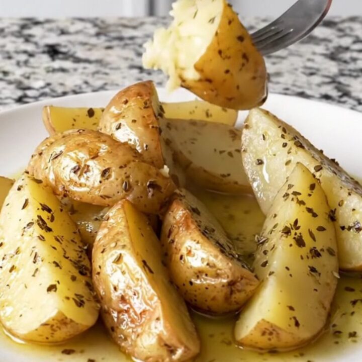 A close-up of tender golden potato wedges in a slow cooker, seasoned with herbs and lemon.
