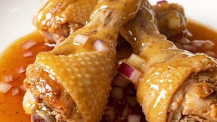 A plate of slow-cooked chicken drumsticks glazed in a thick, glossy ancho honey sauce.