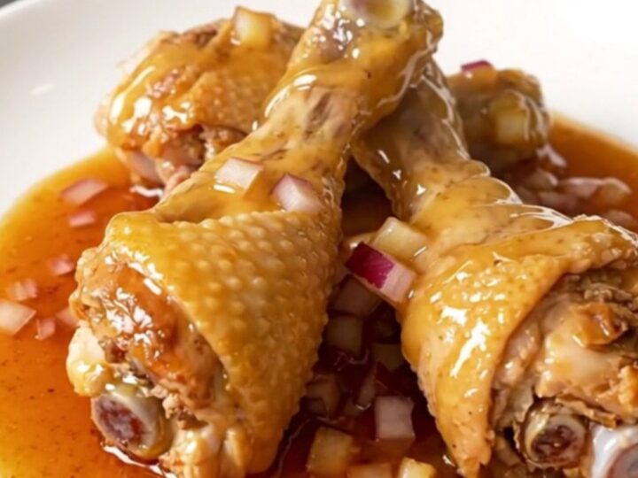 A plate of slow-cooked chicken drumsticks glazed in a thick, glossy ancho honey sauce.