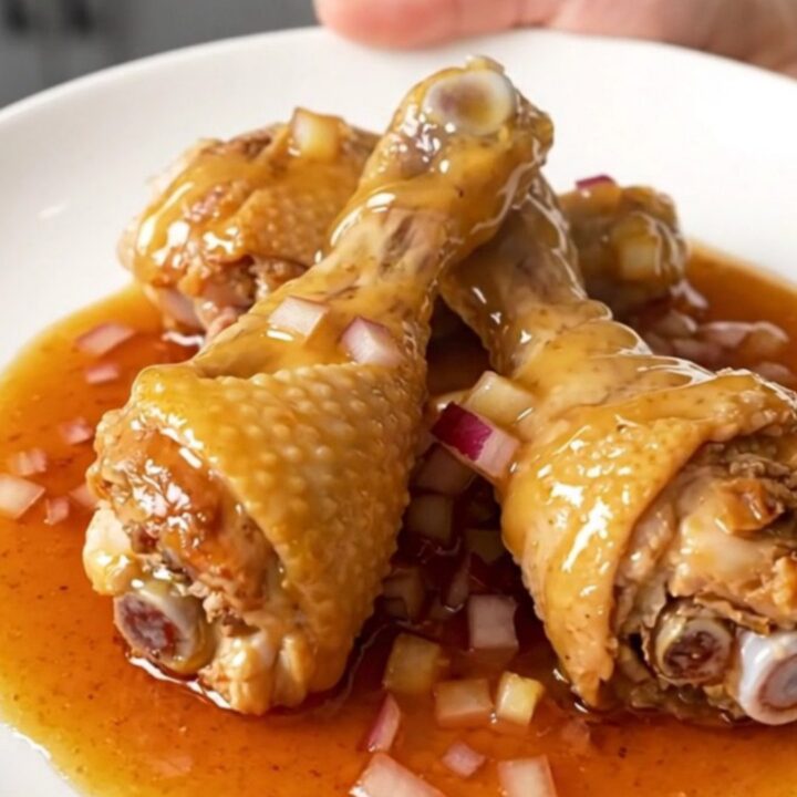A plate of slow-cooked chicken drumsticks glazed in a thick, glossy ancho honey sauce.