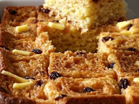 A golden, puffed cinnamon raisin French toast bake in a white ceramic dish.