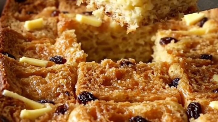 A golden, puffed cinnamon raisin French toast bake in a white ceramic dish.