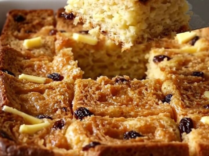 A golden, puffed cinnamon raisin French toast bake in a white ceramic dish.
