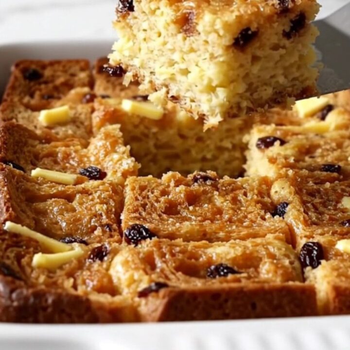 A golden, puffed cinnamon raisin French toast bake in a white ceramic dish.