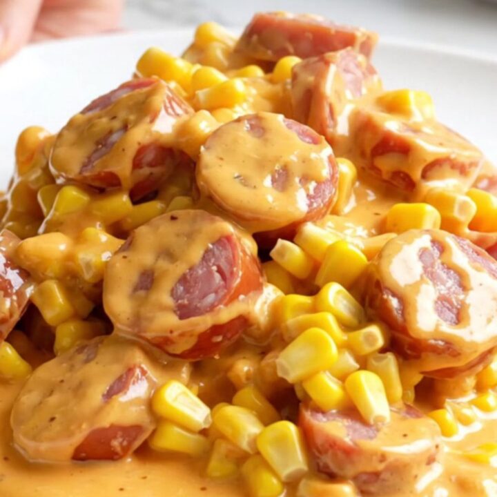 A slow cooker filled with creamy street corn and smoked sausage coins.
