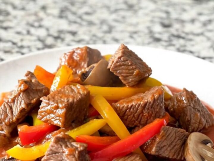 A hearty bowl of slow cooker beef tips cacciatore with peppers and mushrooms in a rich tomato sauce.