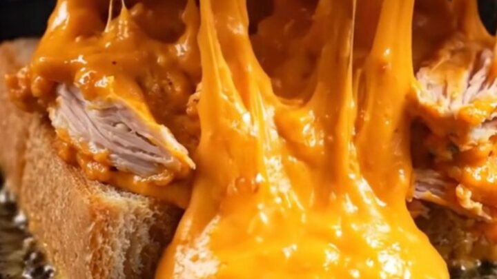 A crispy buffalo chicken melt with a golden cheese crust on golden Texas toast, featuring molten filling.