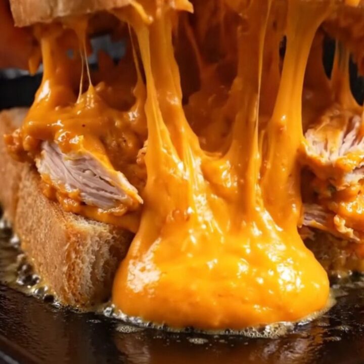 A crispy buffalo chicken melt with a golden cheese crust on golden Texas toast, featuring molten filling.