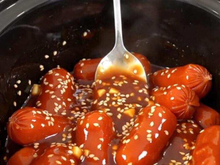 A close-up of honey gochujang cocktail sausages in a slow cooker, glistening with a thick, spicy-sweet glaze.