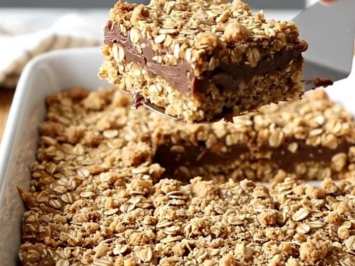 A top-down view of oatmeal fudge revel bars in a white ceramic baking dish on a butcher-block counter.