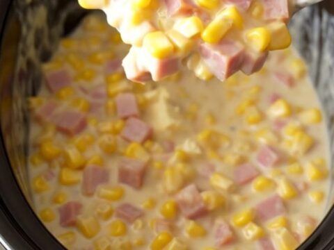 A close-up of a creamy ham and corn mixture in a slow cooker, featuring melted cream cheese sauce.