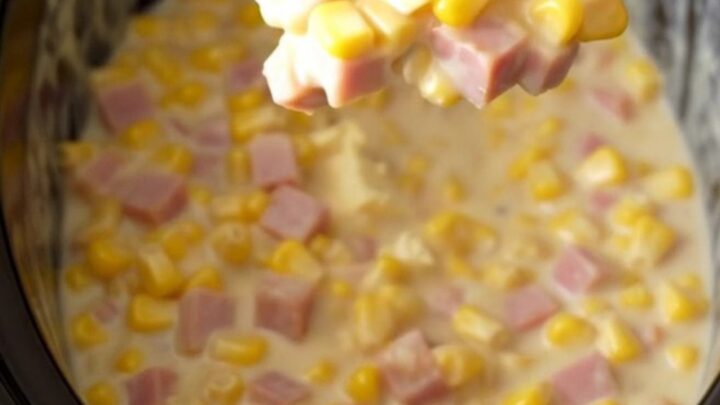 A close-up of a creamy ham and corn mixture in a slow cooker, featuring melted cream cheese sauce.