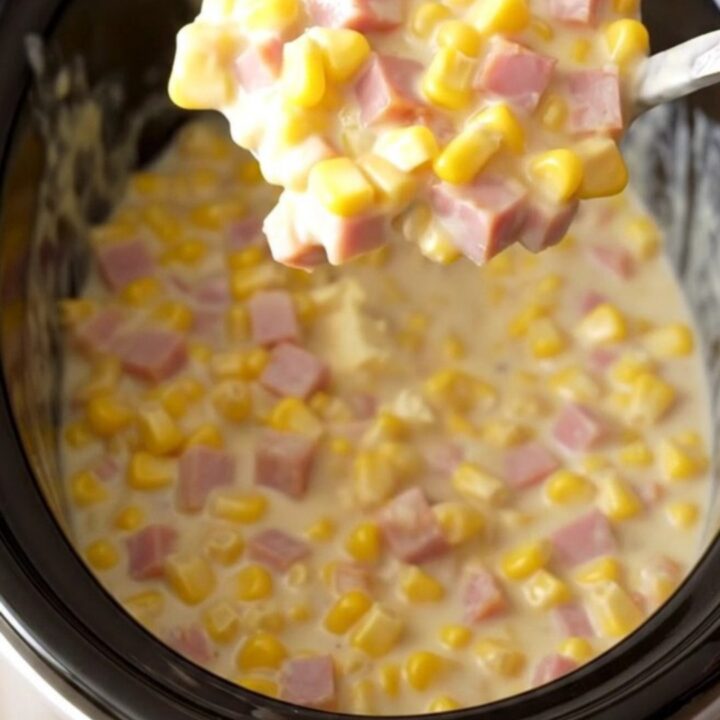 A close-up of a creamy ham and corn mixture in a slow cooker, featuring melted cream cheese sauce.