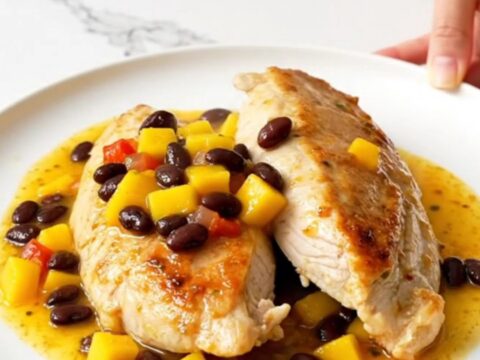 A top-down view of slow cooker mango salsa chicken with black beans served on a white plate.