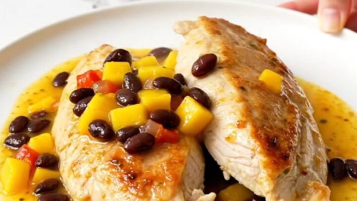 A top-down view of slow cooker mango salsa chicken with black beans served on a white plate.