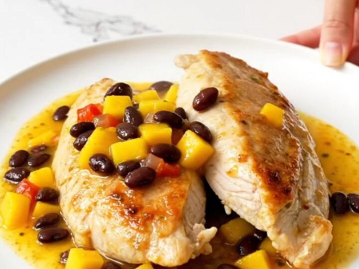 A top-down view of slow cooker mango salsa chicken with black beans served on a white plate.