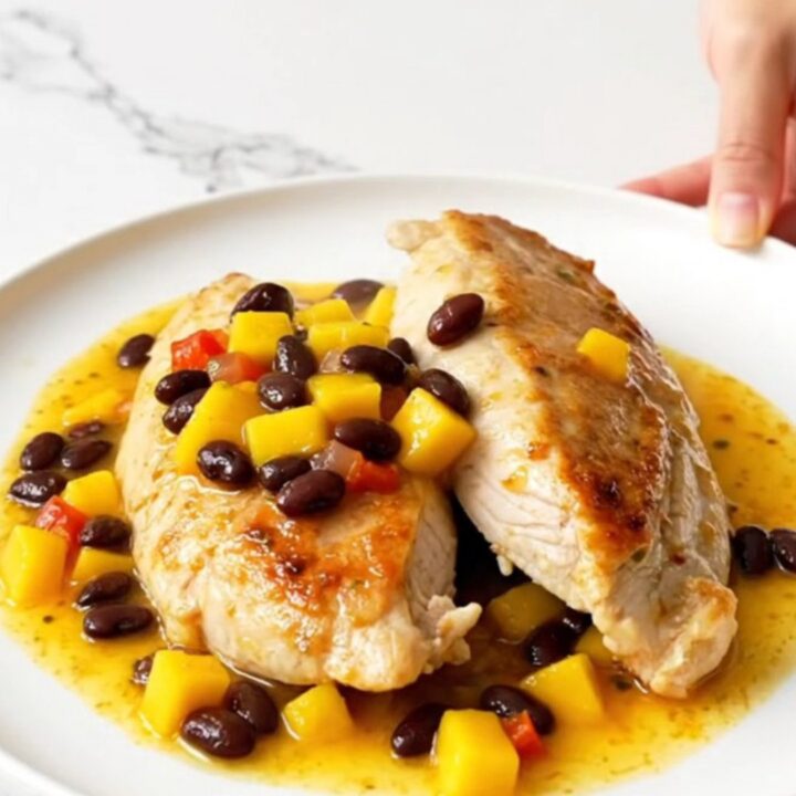A top-down view of slow cooker mango salsa chicken with black beans served on a white plate.