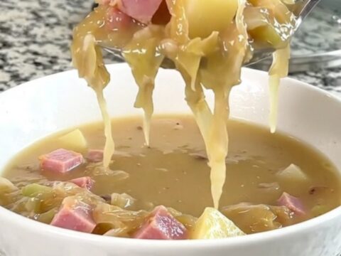A warm, creamy ham and sauerkraut soup in a white bowl with visible chunks of potato and ham.