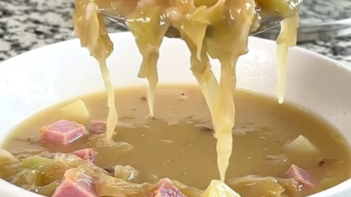 A warm, creamy ham and sauerkraut soup in a white bowl with visible chunks of potato and ham.