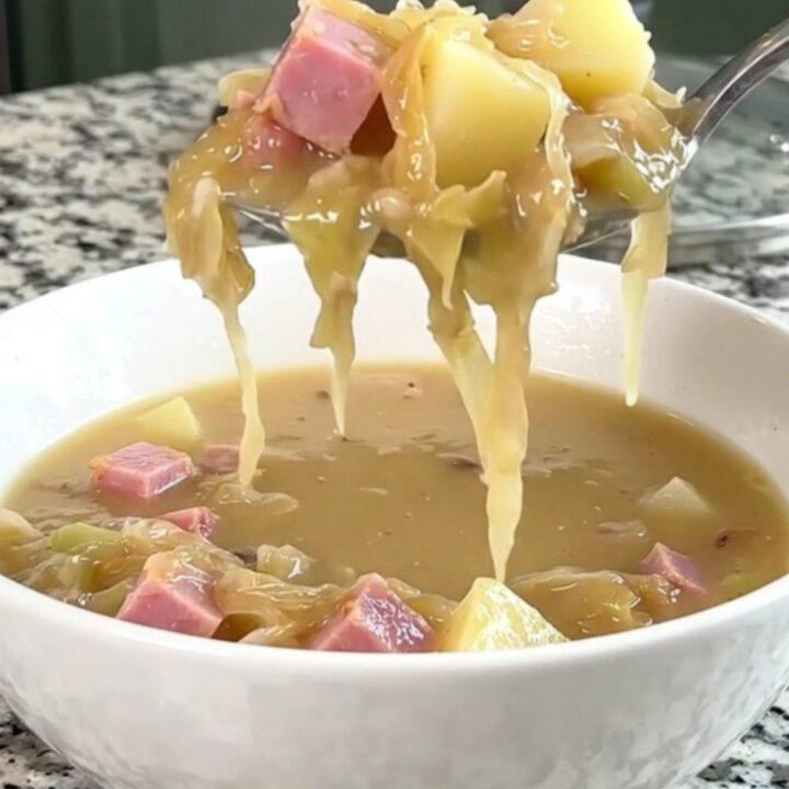 A warm, creamy ham and sauerkraut soup in a white bowl with visible chunks of potato and ham.