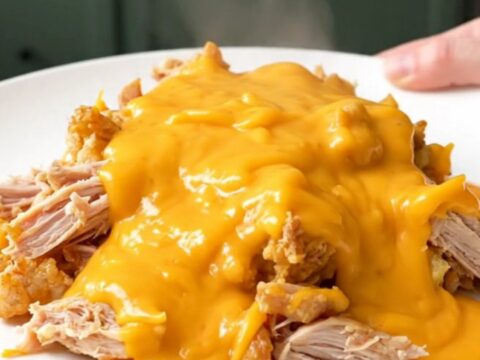 A top-down view of a slow cooker filled with ground turkey and cauliflower florets in a creamy cheddar sauce.