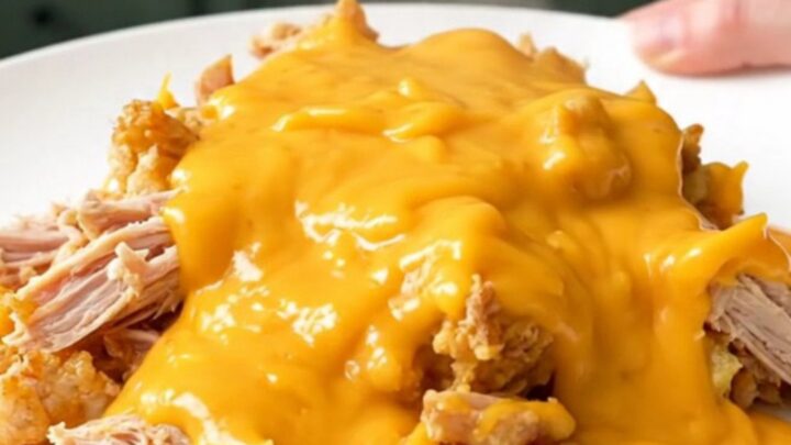 A top-down view of a slow cooker filled with ground turkey and cauliflower florets in a creamy cheddar sauce.