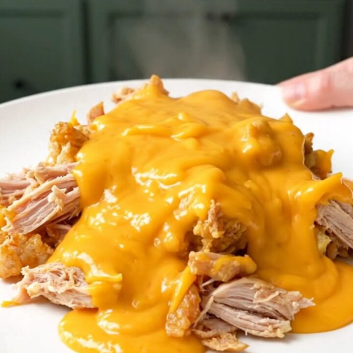 A top-down view of a slow cooker filled with ground turkey and cauliflower florets in a creamy cheddar sauce.
