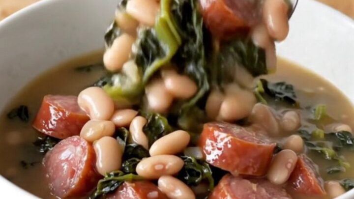 A hearty bowl of Southern swamp stew featuring sausage coins, white beans, and dark greens in a rich broth.