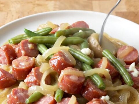 A close-up view of creamy kielbasa and potato stew in a slow cooker, featuring golden potato chunks and sliced sausage.