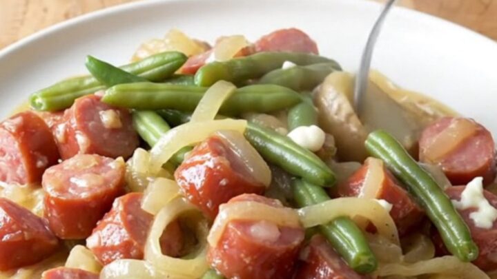 A close-up view of creamy kielbasa and potato stew in a slow cooker, featuring golden potato chunks and sliced sausage.
