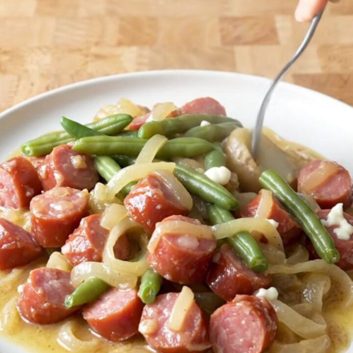 A close-up view of creamy kielbasa and potato stew in a slow cooker, featuring golden potato chunks and sliced sausage.
