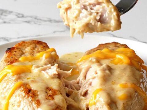 Creamy garlic butter cheddar chicken served on a plain white plate, showing melted cheese and tender white meat.