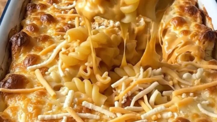 A top-down view of a rectangular baker filled with uncooked cavatappi pasta and a rich, creamy cheese sauce