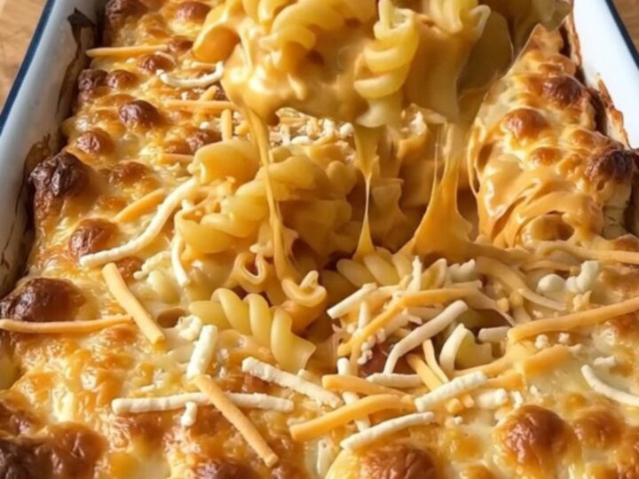 A top-down view of a rectangular baker filled with uncooked cavatappi pasta and a rich, creamy cheese sauce
