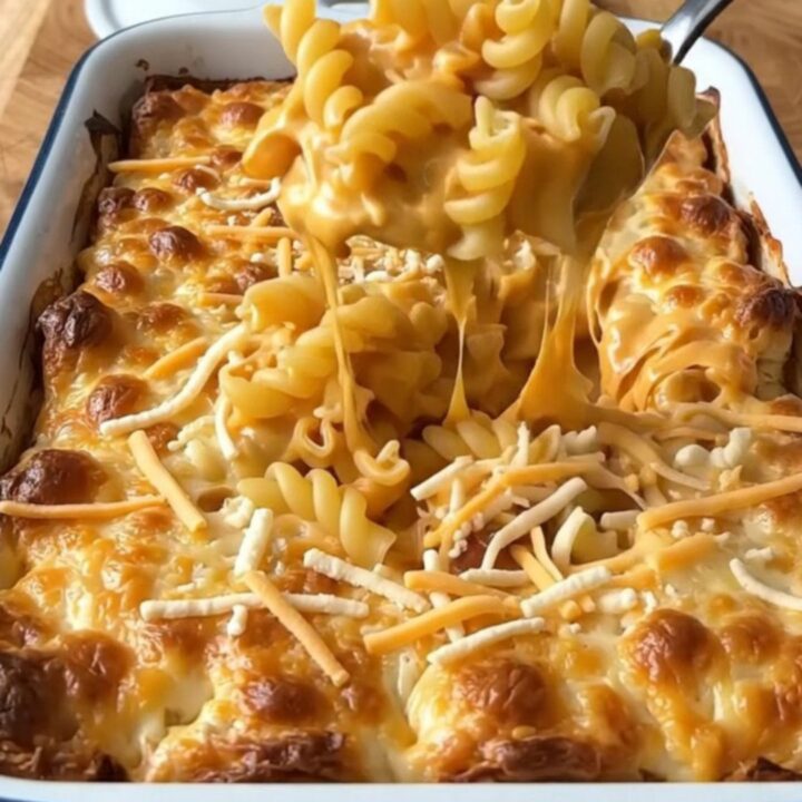 A top-down view of a rectangular baker filled with uncooked cavatappi pasta and a rich, creamy cheese sauce