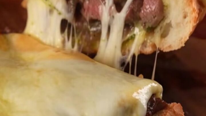 A crispy golden-brown French bread loaf stuffed with Philly cheesesteak filling and melted cheese.