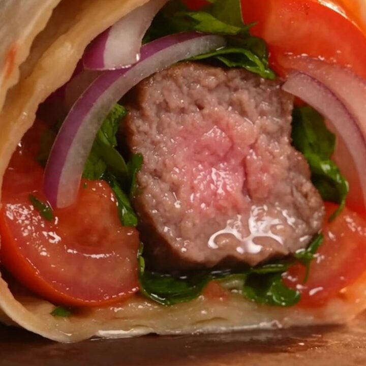 Authentic Turkish Adana kebab featuring juicy lamb on flat iron skewers with charred peppers and tomatoes.