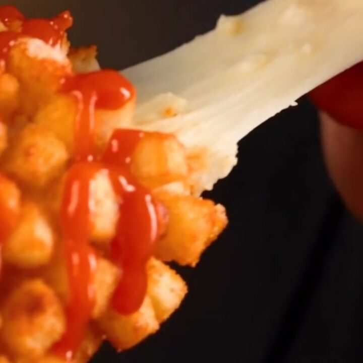 A close-up of a golden-brown crispy potato Korean corn dog being pulled apart to reveal a long