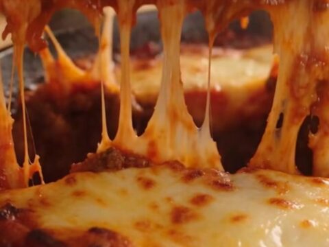 A rustic cast-iron skillet filled with one-pan lasagna featuring bubbling mozzarella and fresh basil.