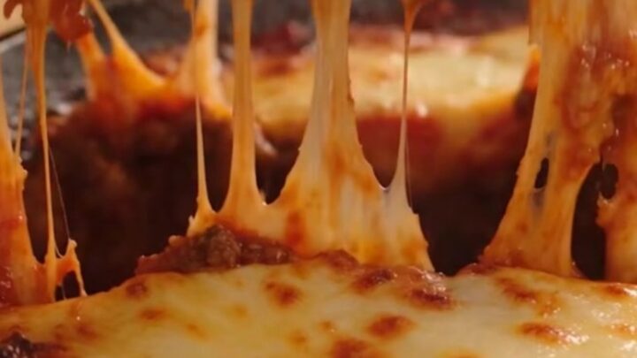 A rustic cast-iron skillet filled with one-pan lasagna featuring bubbling mozzarella and fresh basil.