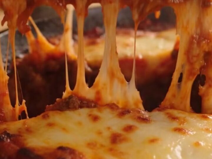 A rustic cast-iron skillet filled with one-pan lasagna featuring bubbling mozzarella and fresh basil.