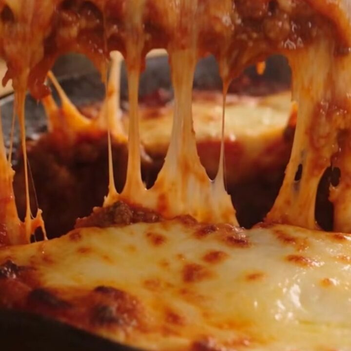 A rustic cast-iron skillet filled with one-pan lasagna featuring bubbling mozzarella and fresh basil.