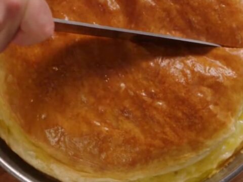 A golden-brown, freshly baked Turkish water borek cut into generous squares on a round tray.