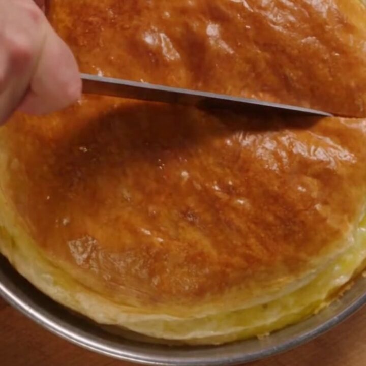 A golden-brown, freshly baked Turkish water borek cut into generous squares on a round tray.