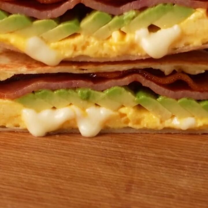 A crispy, golden-brown folded breakfast quesadilla triangle on a marble surface.