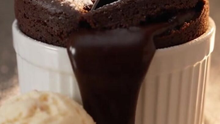A warm molten chocolate lava mug cake in a ceramic mug with a liquid center.