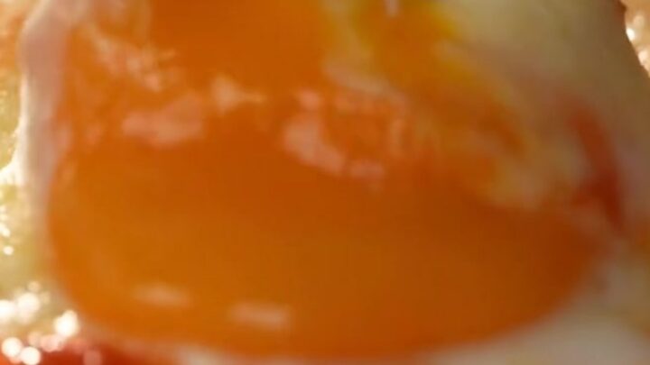 A rustic copper pan filled with bubbling menemen, featuring bright red tomato sauce, soft peppers