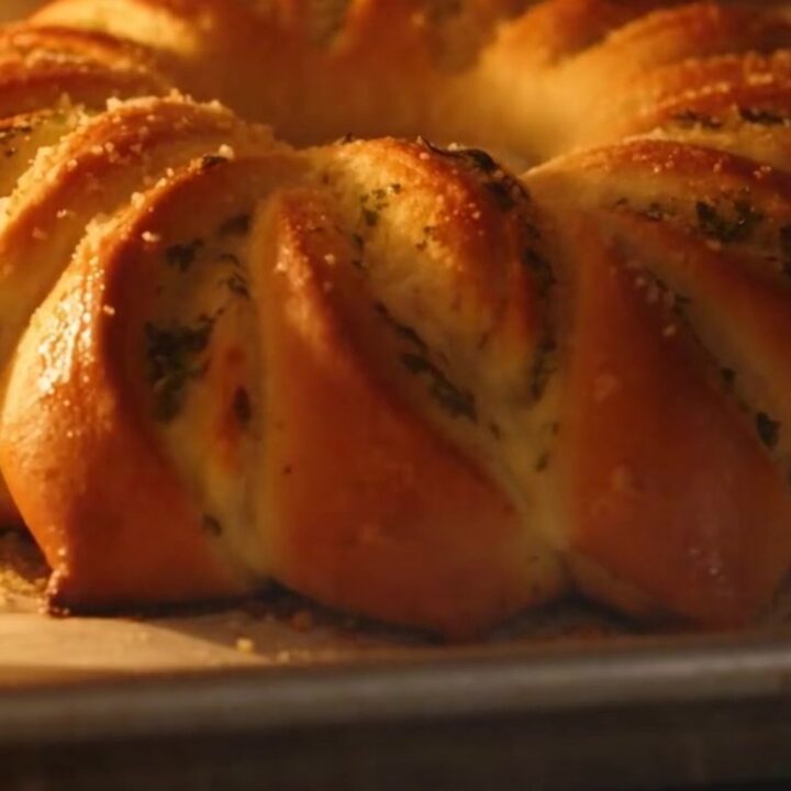 A golden-brown pull-apart garlic herb brioche flower on a wooden board.