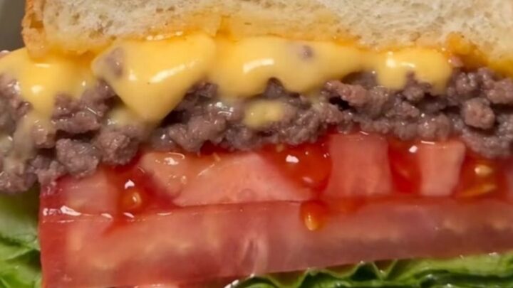 A classic NYC chopped cheese sandwich wrapped in butcher paper, showing the melty beef and cheese filling.